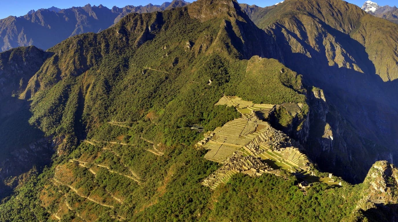 Vista cenital hacia abajo desde la cumbre de Huayna Picchu contemplando la ciudadela de Machu Picchu y la Montaña Machu Picchu al fondo